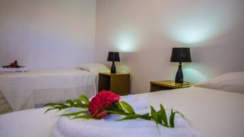 Une chambre d’hôtel avec deux lits, chacun recouvert d’une courtepointe blanche et agrémenté d’une lampe sur une table de chevet en bois.