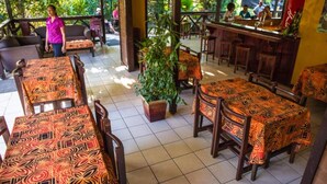 An outdoor restaurant with wooden tables and chairs, covered with patterned tablecloths. - Eden's Edge Hotel (Apia)