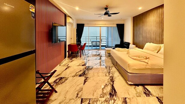 A hotel room with a bed, a TV, a dining area with chairs, a balcony with a table and chairs, and a view of the city. - Vtsix Condo Service at View Talay Condo (Pattaya)