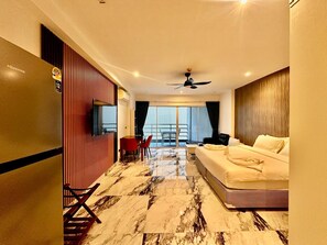 Habitación de hotel con cama, televisor, zona de comedor con sillas, balcón con mesa y sillas, y vistas a la ciudad.