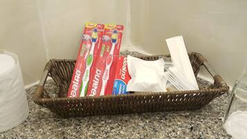 Een rieten mand op een granieten aanrecht met daarin mondverzorgingsproducten, zoals tandpasta en tandenborstels.