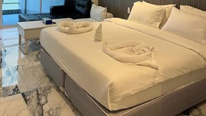 A modern hotel room with a large bed, a ceiling fan, a view of the outdoors, and a wooden accent wall. - Vtsix Condo Service at View Talay Condo (Pattaya)