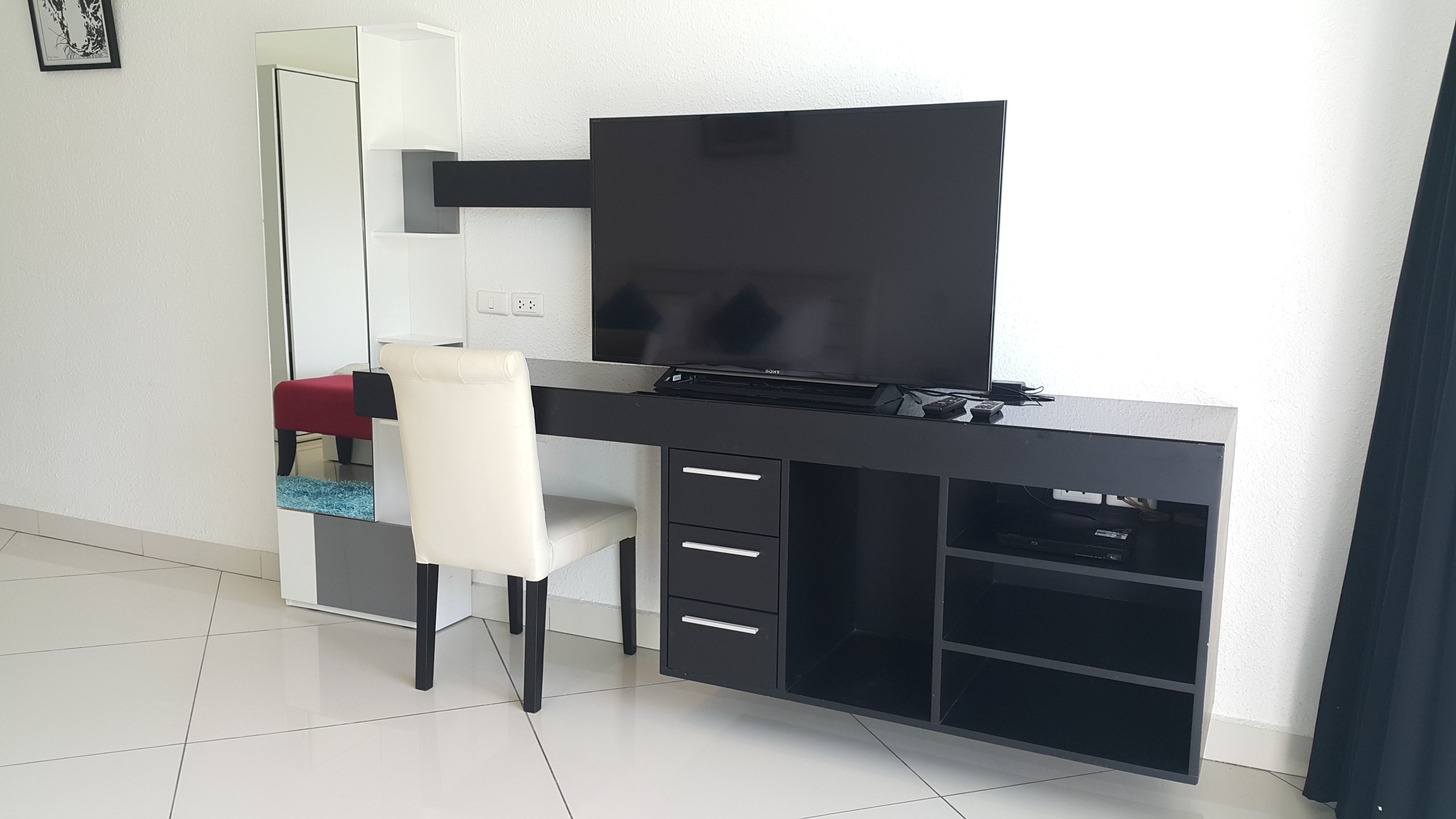 A modern study room with a desk, chair, and shelving unit.