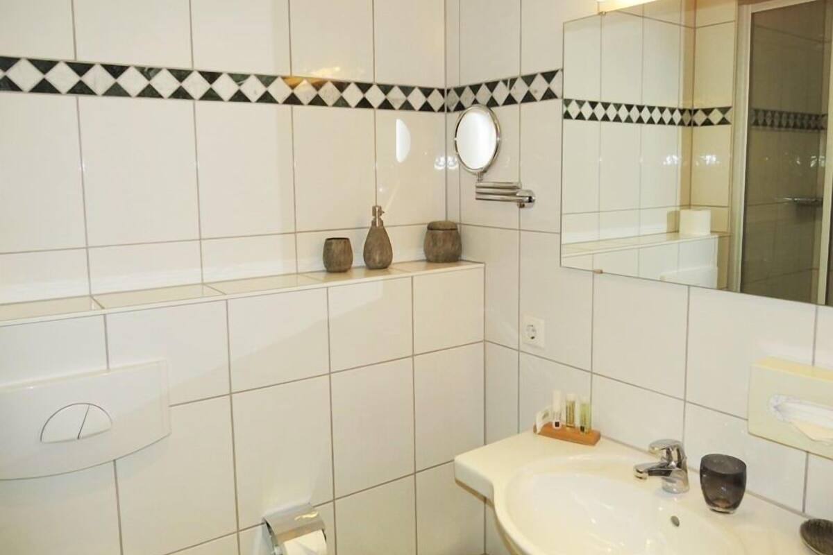 A bathroom with a white sink, mirror, and tiled walls.