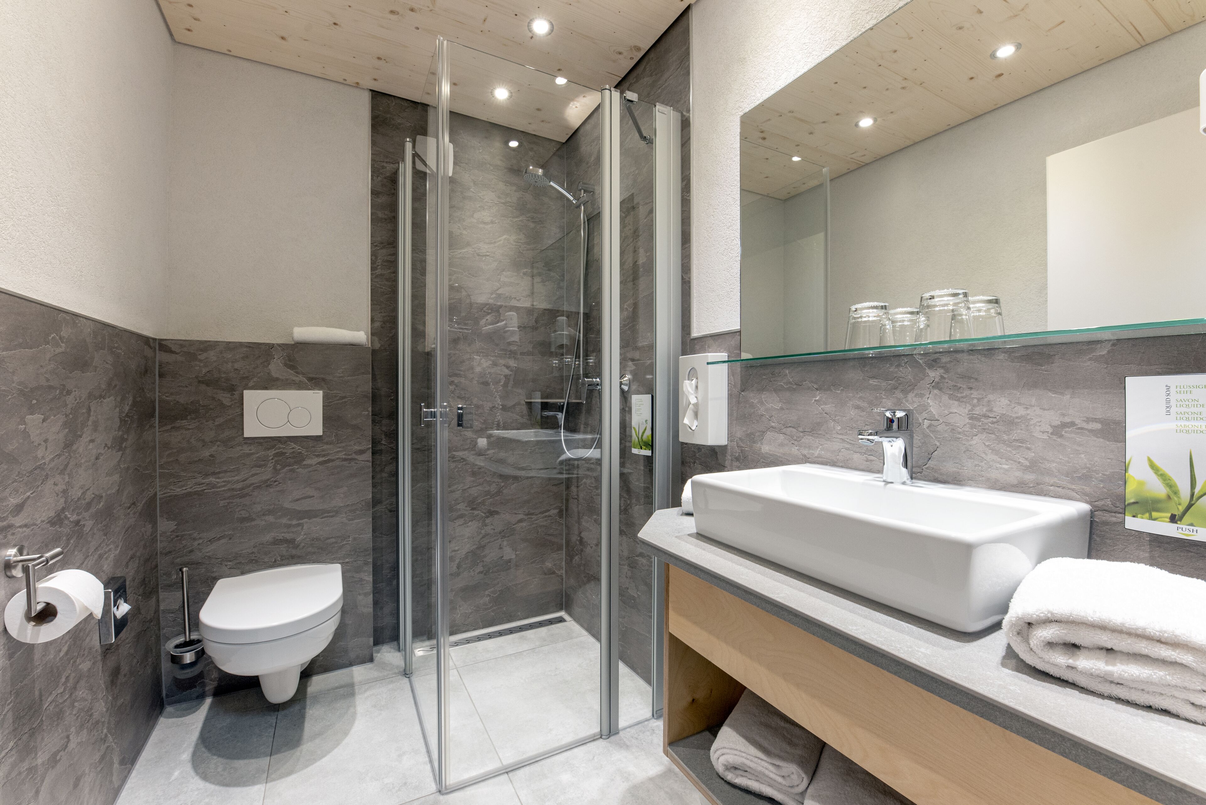 Une salle de bain moderne avec une douche à parois de verre, un lavabo blanc et des toilettes.
