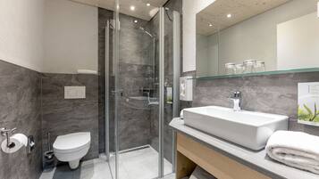 Une salle de bain moderne avec une douche à parois de verre, un lavabo blanc et des toilettes.