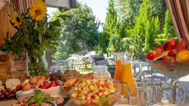 A breakfast buffet with various food items, including fruits, pastries, and beverages, set outdoors with a view of greenery. - Wellnesshotel Sonnenhof & Sonnhalde (Uehlingen-Birkendorf)