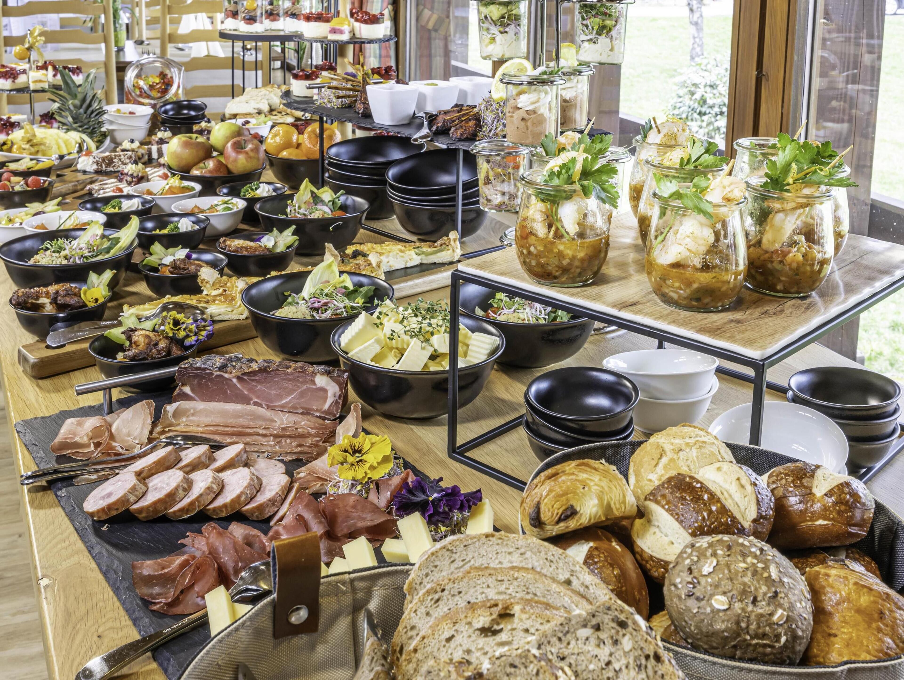 A buffet with various food items including meats, cheeses, breads, and salads.