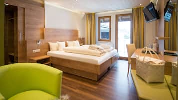 Ein modernes Hotelzimmer mit einem großen Bett, einem Schreibtisch mit Stuhl, einem grünen Sessel und einem an der Wand befestigten Fernseher.