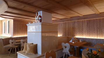 A cozy, wooden interior with a central seating area, a small bar area, and a decorative cabinet with bottles.