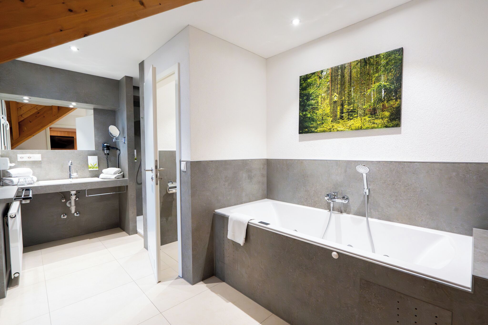 Une salle de bain moderne avec une grande baignoire, un miroir et un lavabo.
