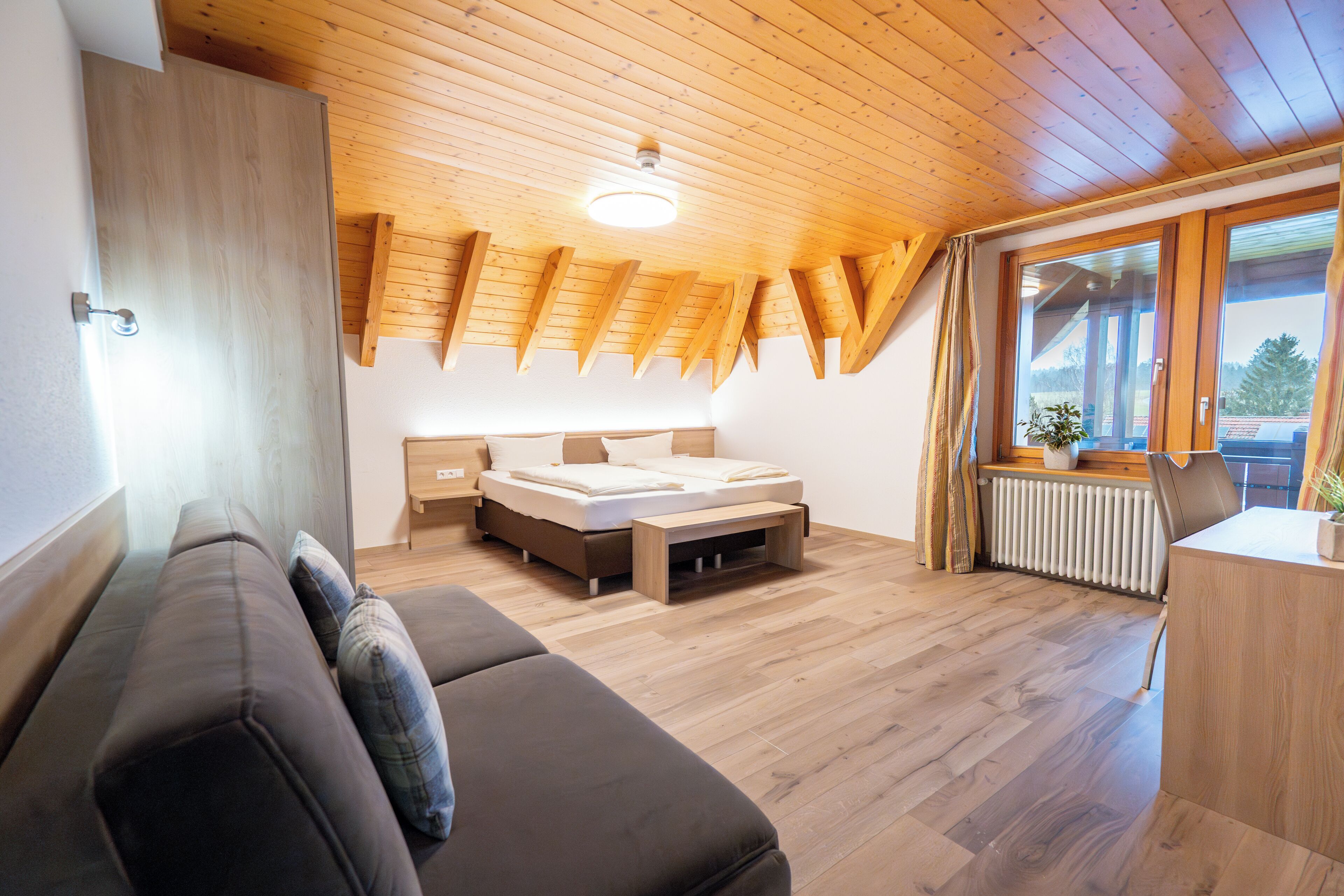 Un dormitorio moderno con cama elevada, techo de madera y vistas al exterior.