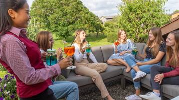 Guests can enjoy casual gatherings in a tranquil outdoor setting surrounded by lush greenery.