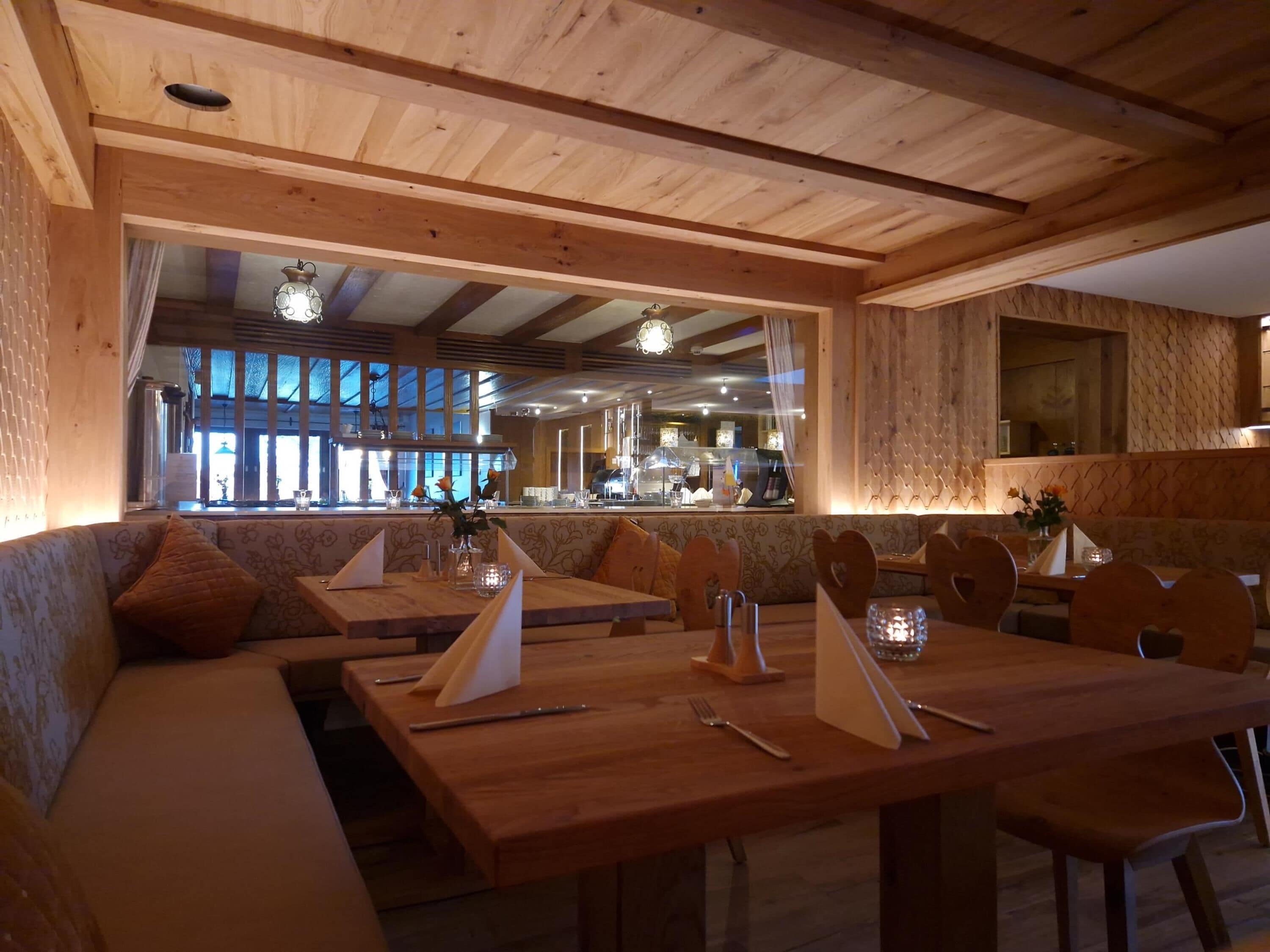 Un restaurante acogedor con mobiliario de madera, una zona de bar y ventanas amplias.