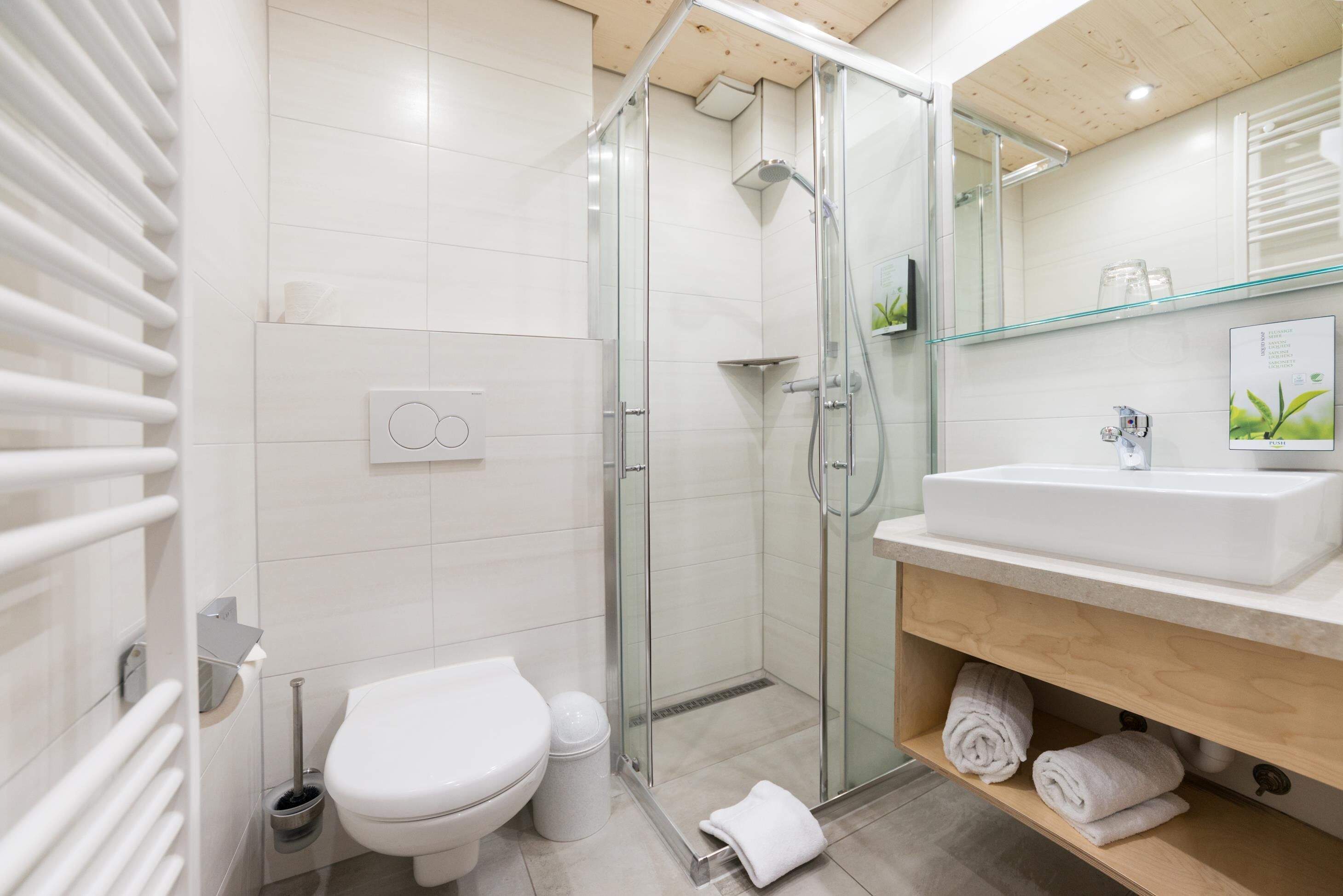 A modern bathroom with a glass shower enclosure, a white toilet, and a sink with a wooden vanity.
