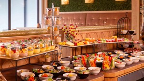 A buffet with various food items and a seating area with a green wall and two wall-mounted lights. - Wellnesshotel Sonnenhof & Sonnhalde (Uehlingen-Birkendorf)