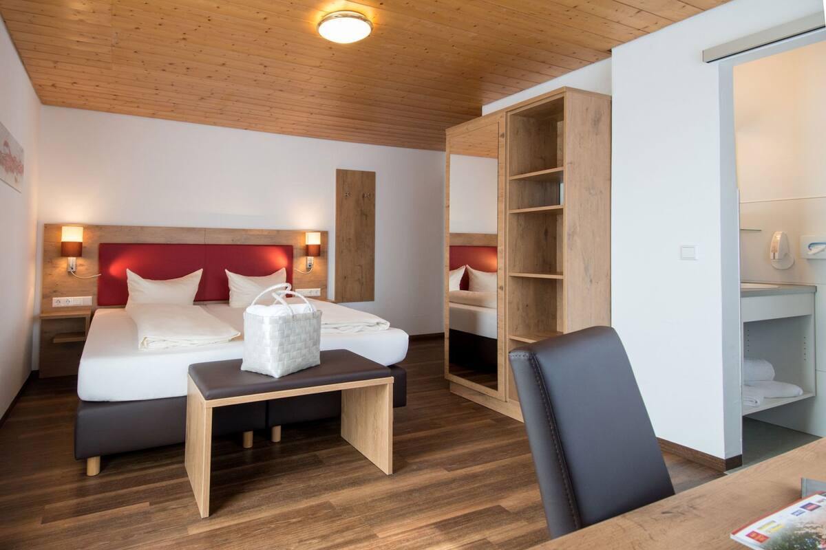 Ein Hotelzimmer mit Bett, Nachttischen, Schreibtisch und Kleiderschrank.