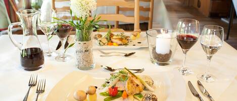 A dining table set with plates of food, wine glasses, and cutlery.