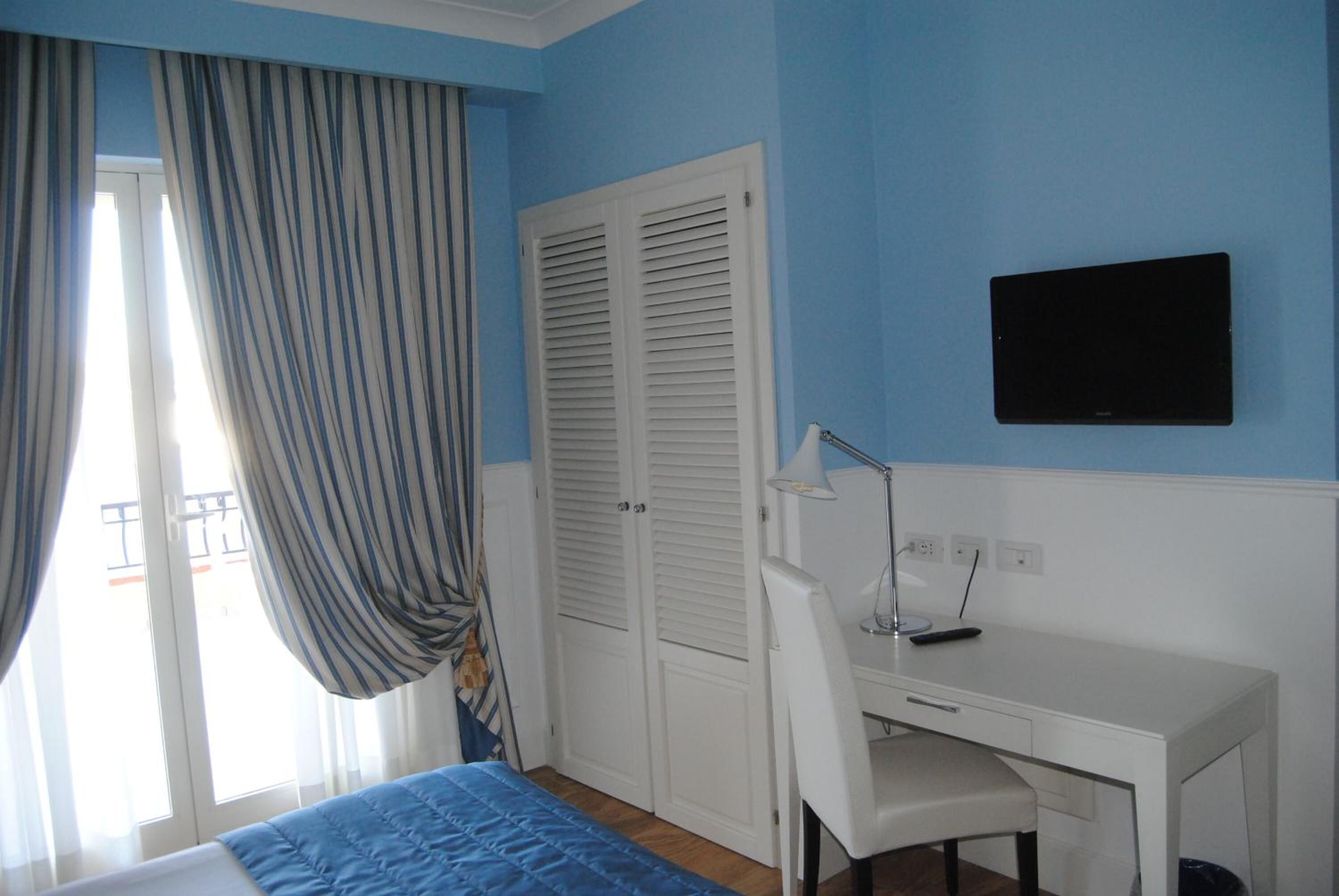A bedroom with a bed, a desk, a chair, a TV, and a wardrobe.