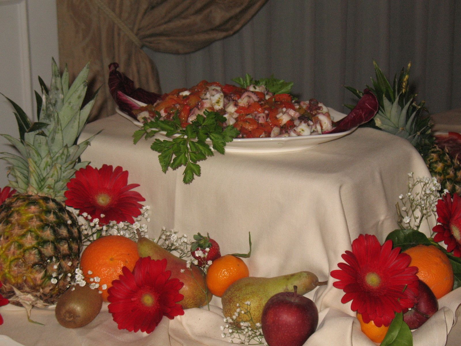 A table with a plate of food, fruits, and flowers.