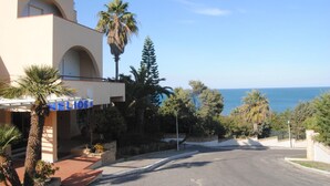 Een hotel in mediterrane stijl, met boogvormige balkons en uitzicht op zee.