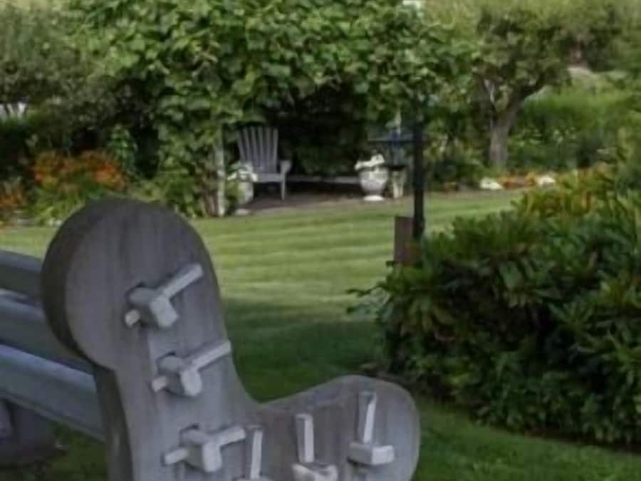 A bench with a backrest and armrests in a garden setting.