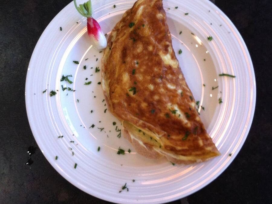 A plate with a folded omelette garnished with herbs.