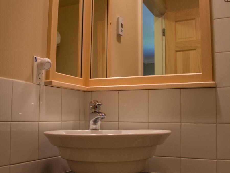 A bathroom with a white sink, a mirror, and a towel dispenser.