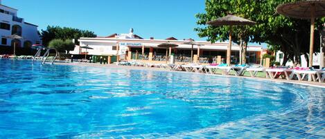 Una piscina al aire libre, sombrillas, tumbonas