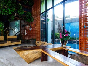 A modern indoor space with a wooden bench, wicker furniture, and a view of a pool through large windows.