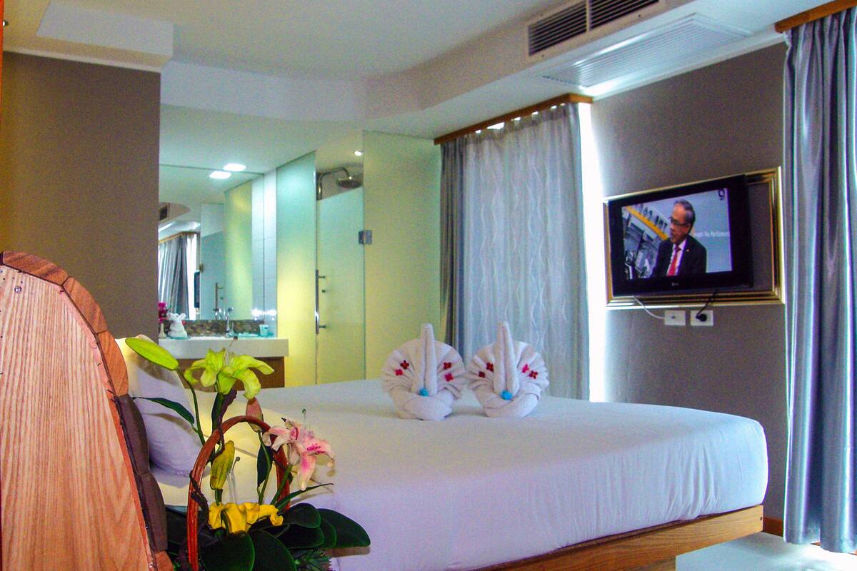 A hotel room with a bed, a television, a bathroom, and a mirror.