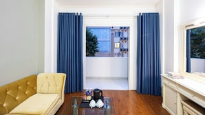 A modern living room with a sofa, a coffee table, and a view of a balcony with blue curtains.