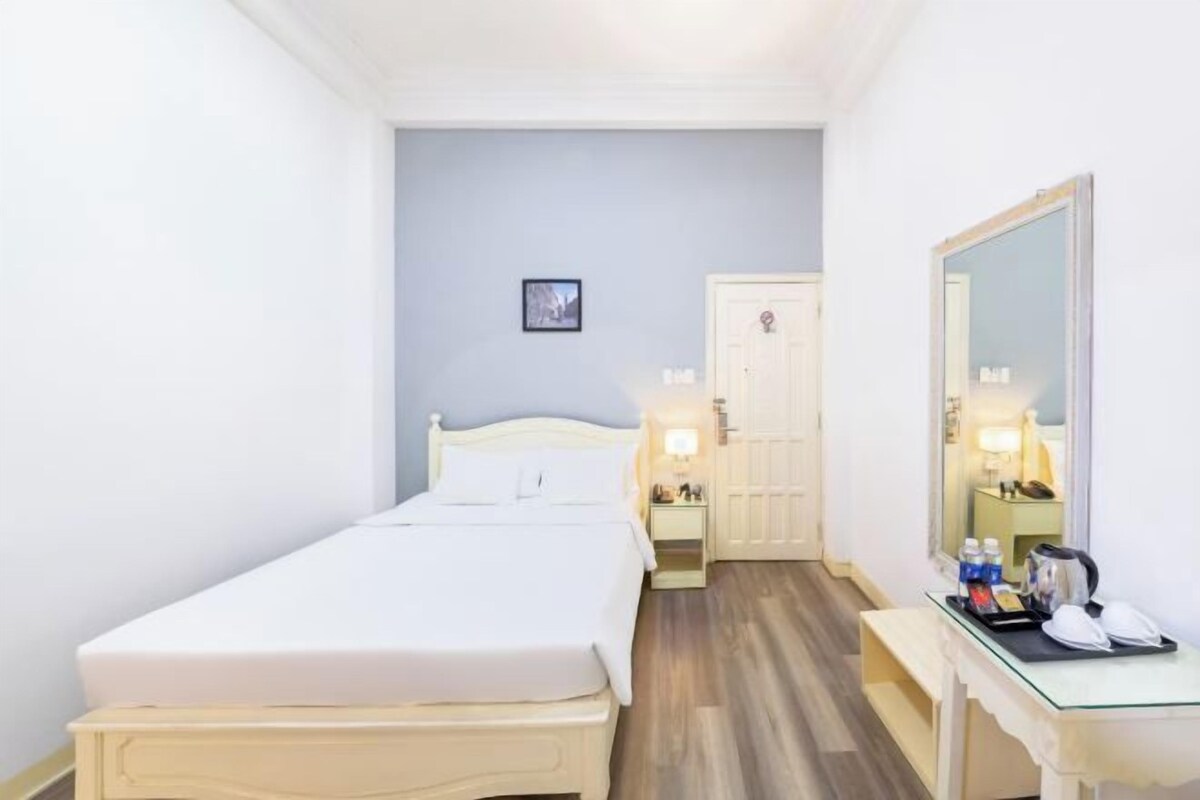 Habitación de hotel con cama, mesita de noche y espejo.