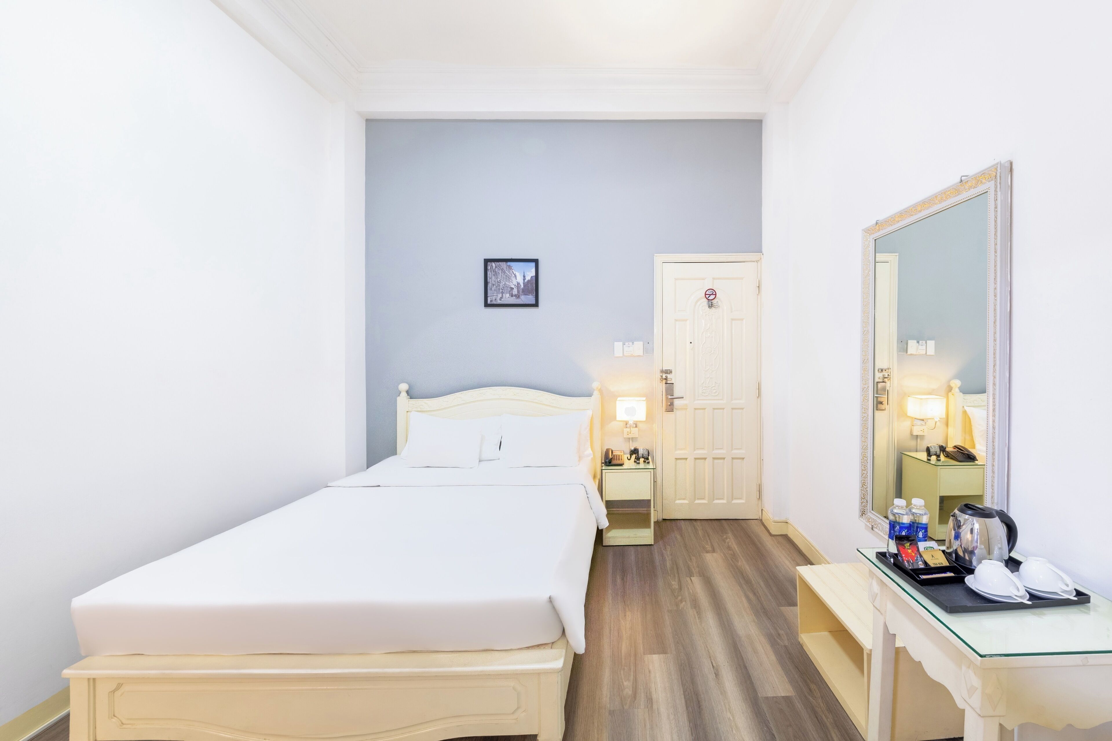 Une chambre d’hôtel avec un lit, une table de chevet et un miroir.