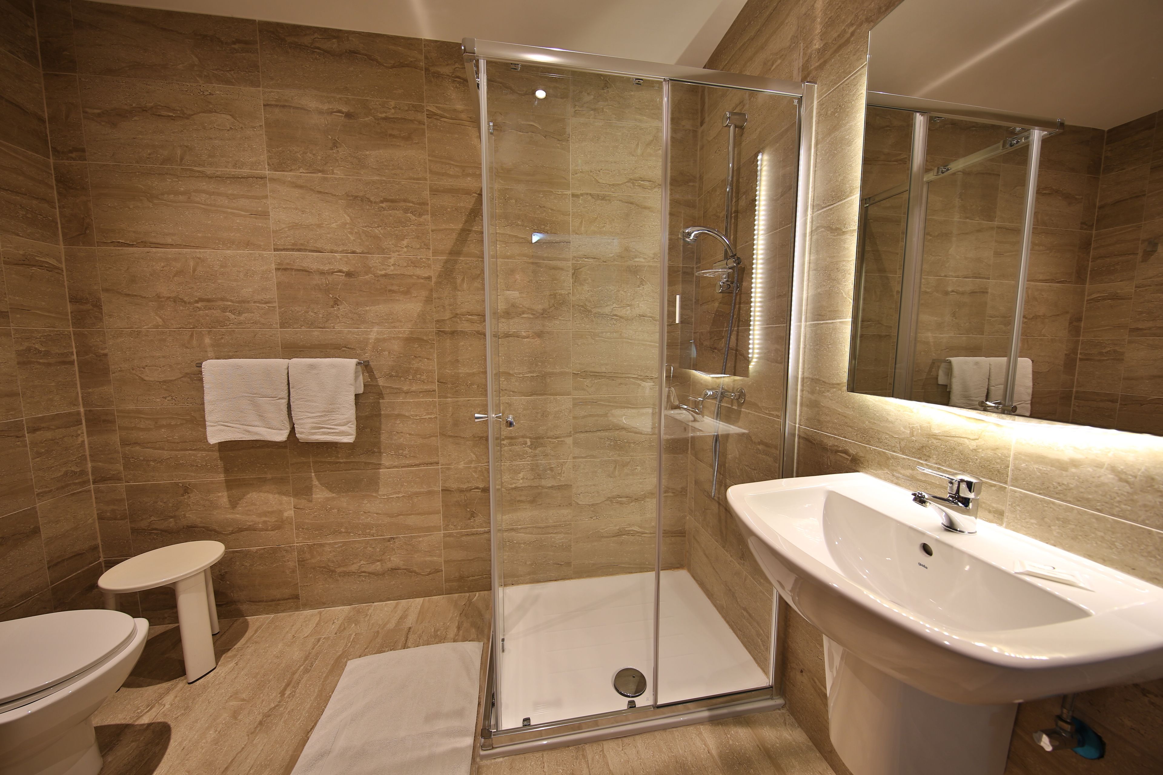 A modern bathroom with a glass-enclosed shower, a white sink, and a toilet.