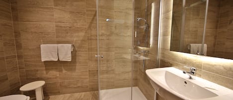 A modern bathroom with a glass-enclosed shower, a white sink, and a toilet.