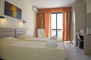 Une chambre d’hôtel avec deux lits, un bureau, une chaise et un tableau au mur.