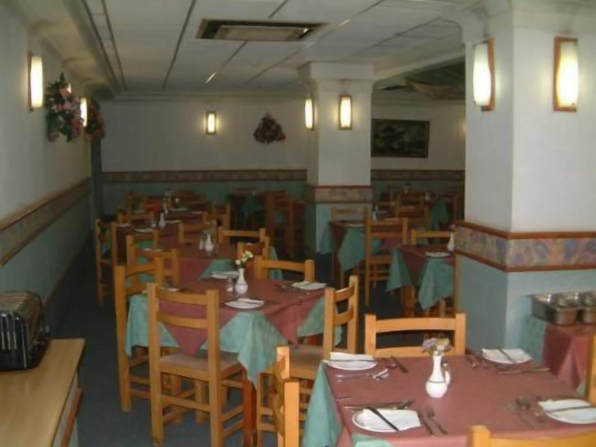 Un restaurante con varias mesas y sillas, cada conjunto con manteles y cubiertos.