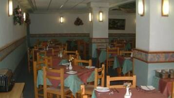 Un restaurante con varias mesas y sillas, cada conjunto con manteles y cubiertos.