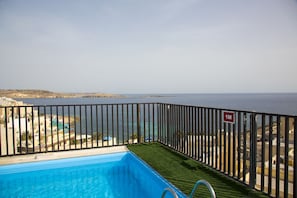 A balcony with a pool, a view of the sea, and a '1M' sign.