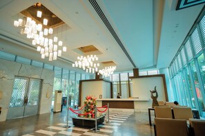 A hotel lobby with a reception desk, a floral centerpiece, and a check-in area. - Oodles Hotel Chhattarpur South Delhi (New Delhi)