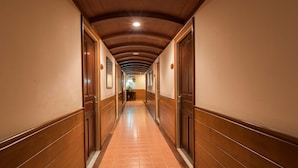 A long, narrow hallway with wooden paneling on the walls and ceiling, leading to a door at the end.