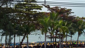 A beach with palm trees, umbrellas, and people.