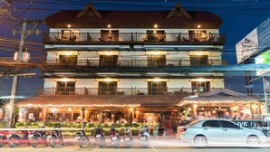 A multi-story building with balconies, a restaurant at the ground level, and a signboard advertising a sale.