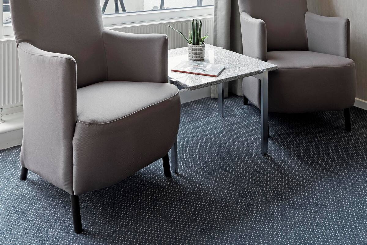 Ein Hotelzimmer mit zwei Sesseln, einem kleinen Tisch und Blick auf Grün.