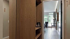 Een gang met houten lambrisering, een bureau met stoel, en een bed op de achtergrond.