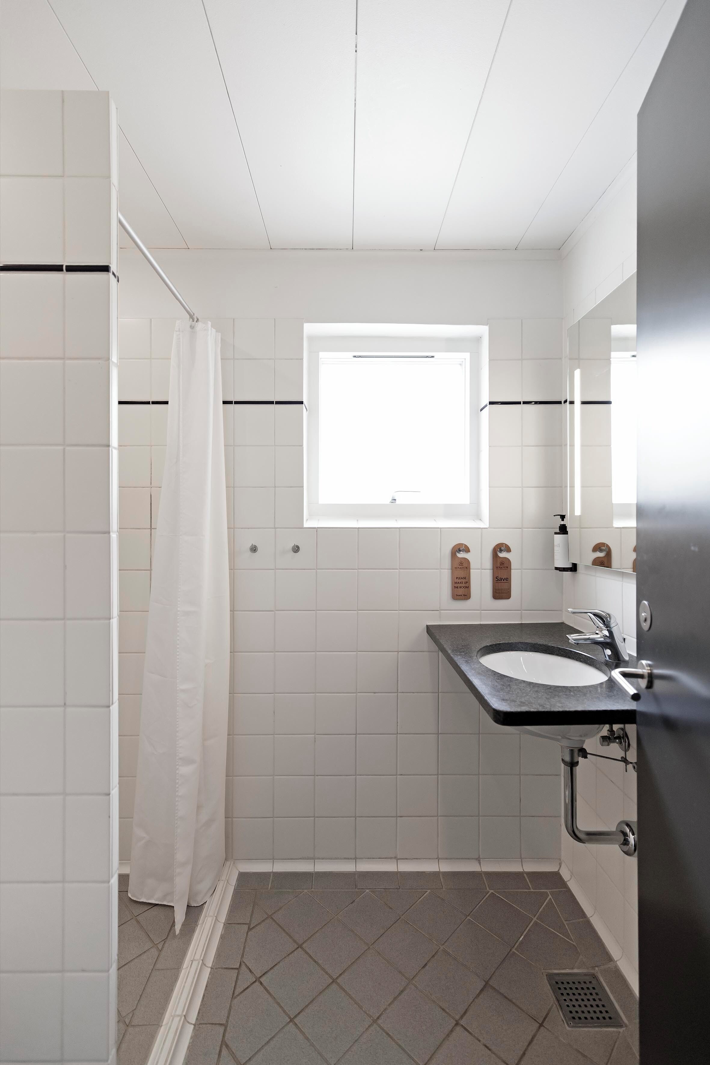Et badeværelse med brusebad, håndvask og et vindue.