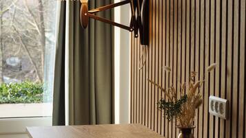 Ein Holztisch mit einer Lampe, einer Vase mit Trockenpflanzen und einer Tastatur auf einem an der Wand befestigten Regal.
