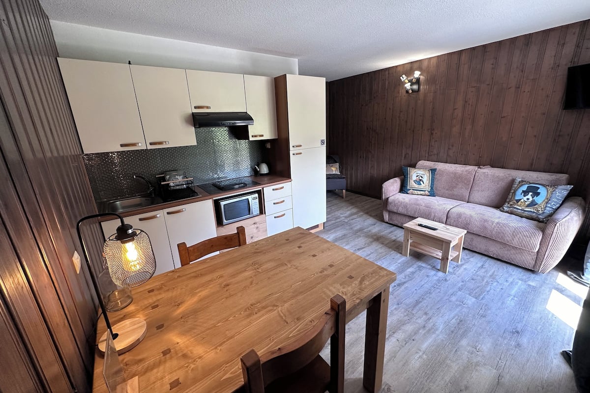 A compact living space with a kitchenette, a dining table, and a sofa.