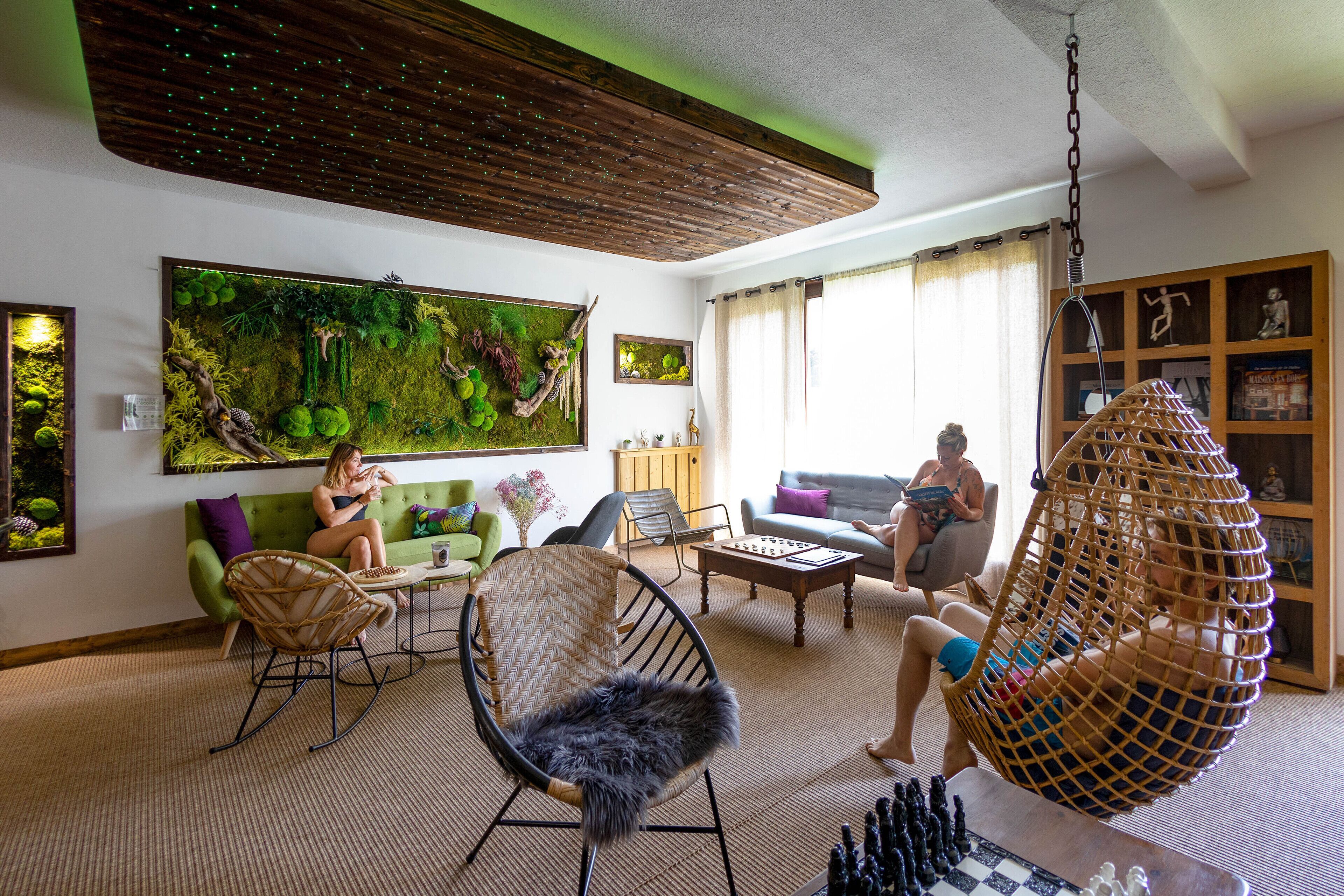 Una sala acogedora con un sofá verde, una silla colgante y una mesa de centro.